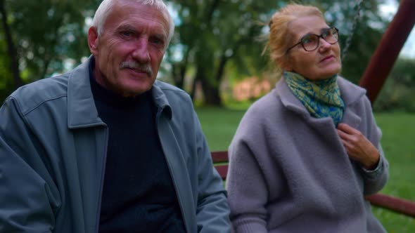 Senior Couple Relaxing Sitting On A Wood Porch Swing At The Public Park In Lithuania. - Handheld Bac