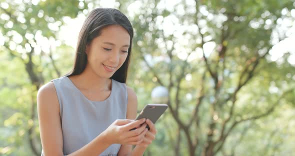 Woman looking at smart phone in the park 