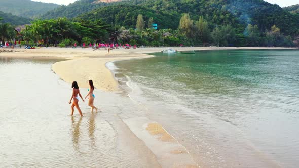 Girls happy together on tropical resort beach lifestyle by blue ocean with clean sandy background of