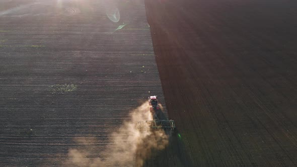 Aerial View Modern Red Tractor on the Agricultural Field on Sunset Time. Tractor Plowing Land