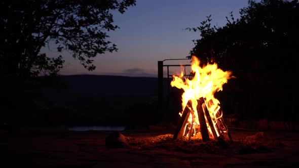 A Bonfire Burns in the Middle of the Night. Fire on the Background of the River and Mountains.