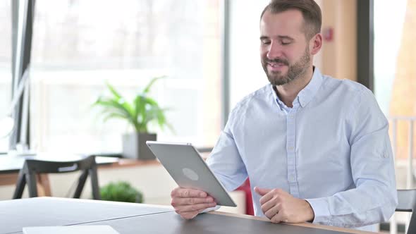 Online Video Chat on Tablet By Young Man in Office 