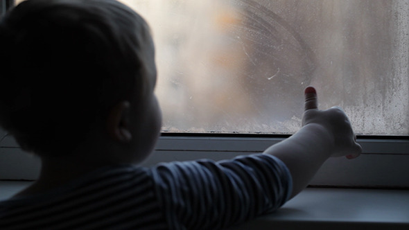 Little Boy Watching Through The Misted Window