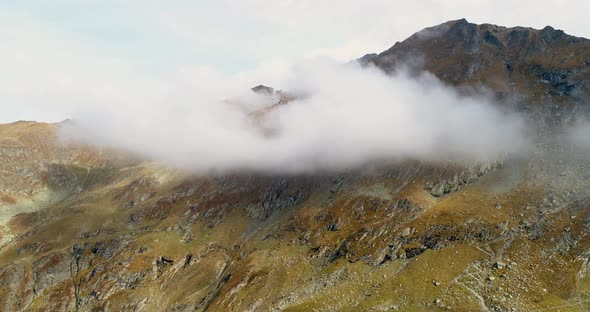 top of the ridge of a rocky mountain in the cloud. mountains with green mog through the clouds