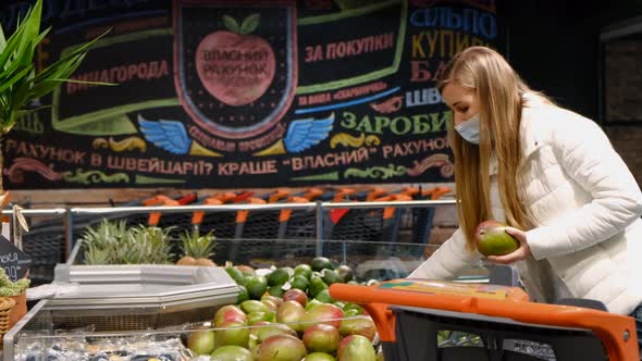 Young woman buys mangoes at the fruit market.