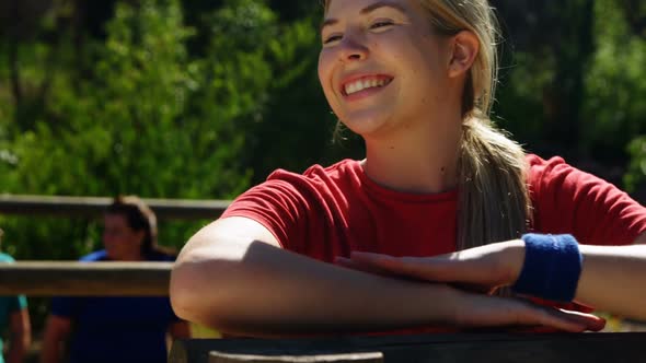 Portrait of female trainer leaning on wooden frame during obstacle course