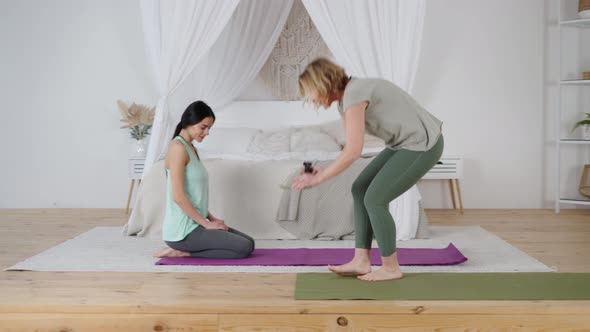 Female Yoga Instructor and Yomg Woman Preparing for Private Lesson at Home