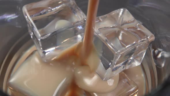 Irish cream liqueur is poured into a glass with ice cubes.