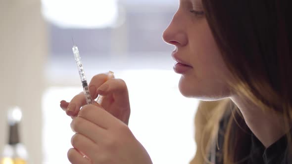 Side View of a Young Bad Looking Woman Preparing the Syringe for Injection