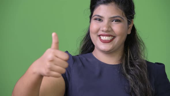 Young Overweight Beautiful Indian Businesswoman Against Green Background