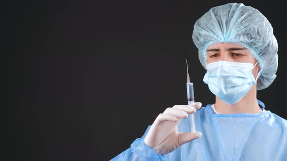 Professional Male Doctor Holds a Syringe with a Vaccine on a Black Background