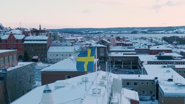 Orbiting aerial shot of Swedish flag in Östersund on a fall day