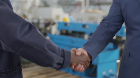  Unrecognizable Factory Worker and Businessman Shaking Hands