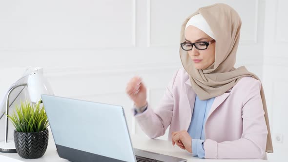 Tired Muslim Woman Works and Types on Laptop Puts Off Her Glasses and Rubs Her Eyes