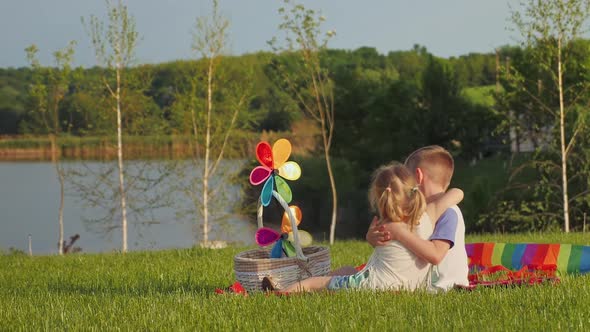 Little Boy and Girl Hug Each Other While Sitting on the Grass