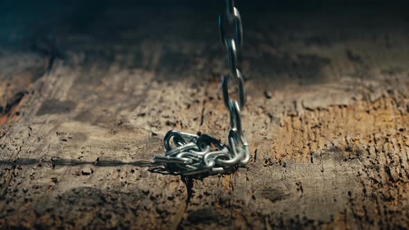 Iron Chain Falling Down Into an Aged Wooden Floor