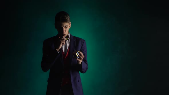 Intelligent Boy in Suit Is Solving Rubik's Cube in Dark.