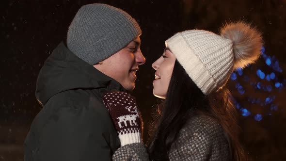 Young Couple Kisses Under Holiday Winter Illumination at Night