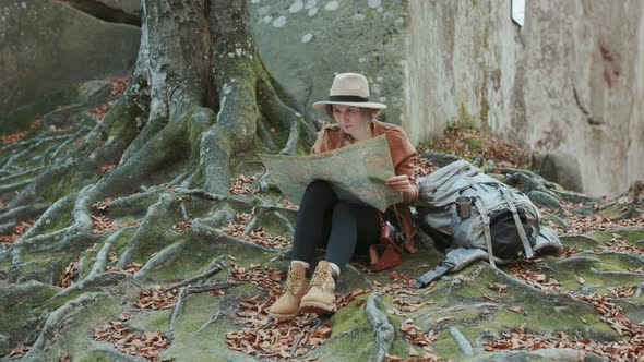 Young woman in stylish hat and shirt looking to the tourist map