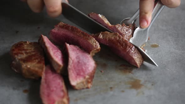 Chef cutting prepared beef steaks with knife, close up