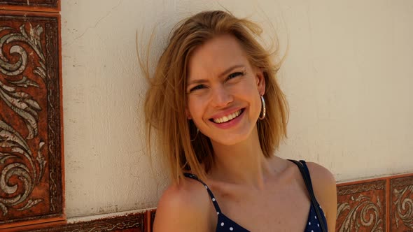 Gorgeous Woman Leaning Against the Cement Wall Smiling