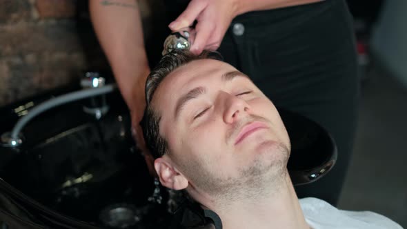 Close-up. Stylist Washes the Hair of the Man in the Beauty Salon or Barbershop. Hairdresser Man