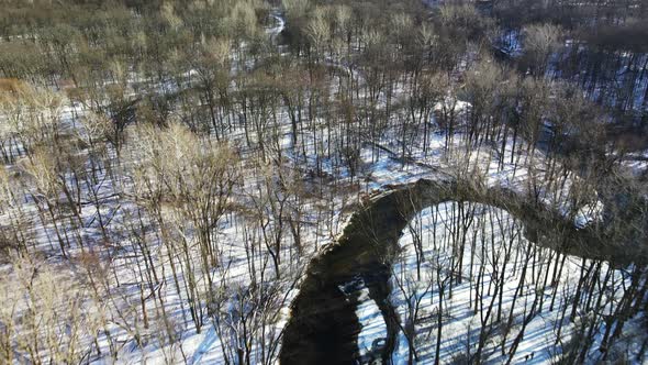 Drone footage above winding stream in winter forest