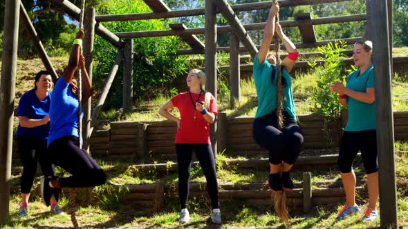 Female trainer assisting women in rope climbing