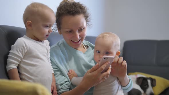 Happy Mother Plays Fun Online Games with Curious Baby Siblings on Phone