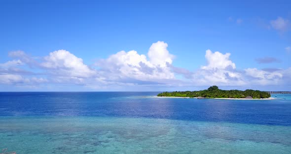 Paradise tropical island in the middle of blue turquoise waters of calm lagoon under a bright blue s