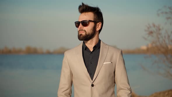 Guy In Sunglasses Walks On Sand And Dreaming. Man Walking On City Beach.  Man Walking On Sand Beach