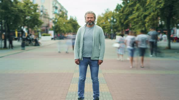 Zoomin Time Lapse Portrait of Serious Mature Man Standing Outside in Street with People Rushing