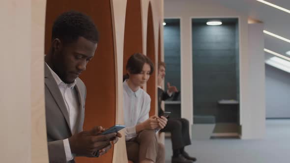 Three Young Businesspeople Using Smartphones