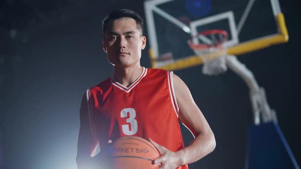 Slow Motion Portrait of an Asian Man Basketball Player Holding a Ball in Her Hands and Serious