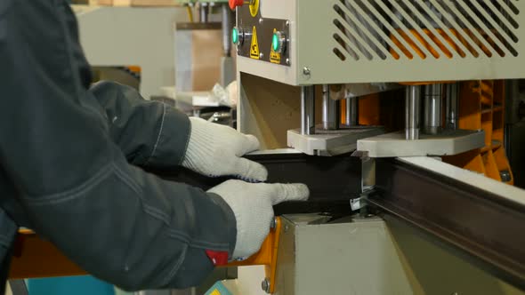 Factory Windows. Worker Inserts the Profile Into the Machine. Production of Window Designs