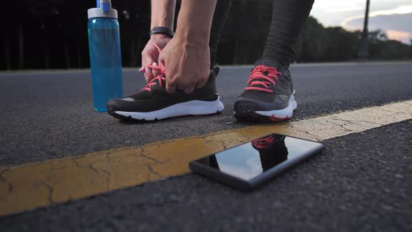 Female Runner Tying Laces on Sneakers Outdoors