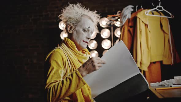 Mime in Costume Opens Script Underlining Lines with Pencil