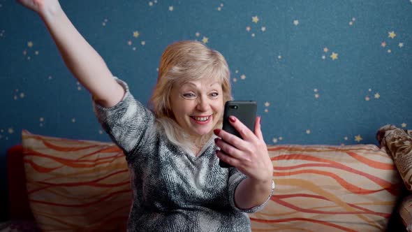 Excited happy senior old 60s woman customer winner holding smartphone using mobile app lottery