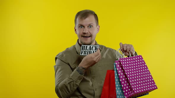 Joyful Man Showing Black Friday Inscription From Shopping Bags, Smiling Satisfied with Low Prices