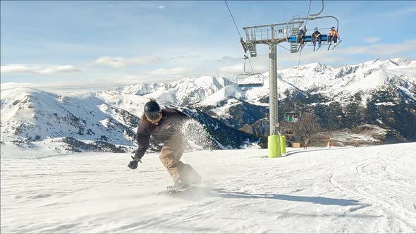 Action follow a male snowboarder goes down the Grandvalira ski resort, carving and jumping