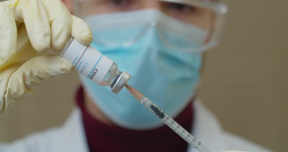 Medical with Face Mask Filling a Syringe with Vaccine