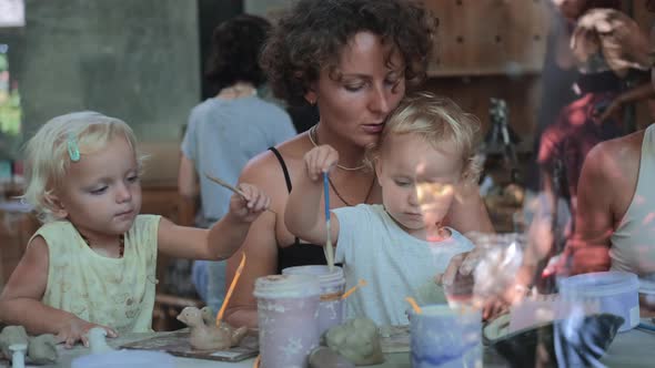 Mom with Two Charming Daughters at a Master Class in Clay Modeling