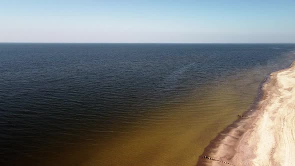 Aerial high altitude view of sea waves crashing into the beach with white sand on a sunny spring day