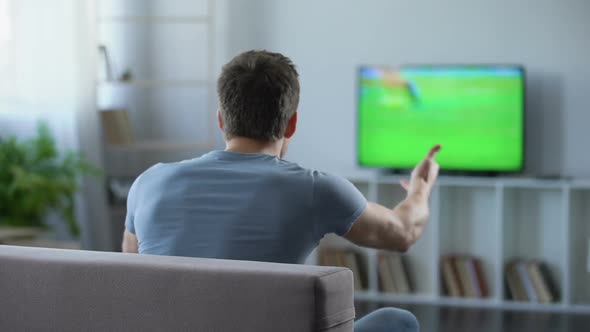 Man Watching Football Match on Big Screen at Home Cheering His Favorite Team