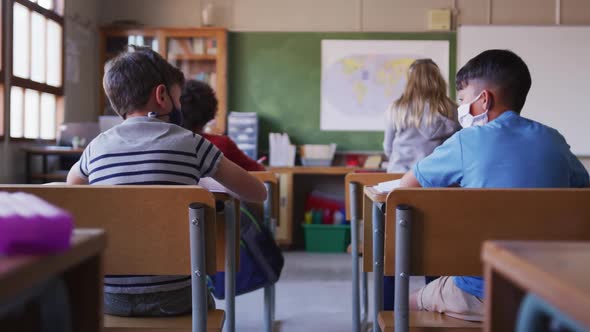 Two boys wearing face masks greeting each other by touching elbows at school