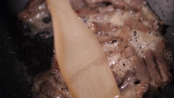 frying beef in oil in a pan