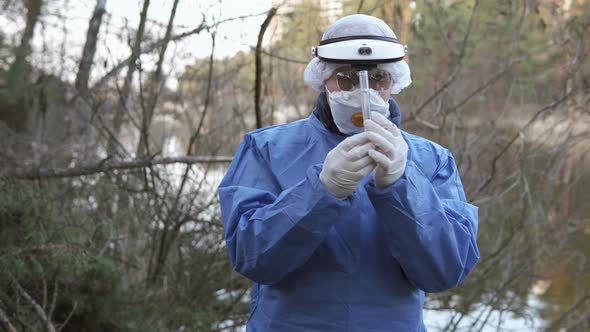 A biologist takes water samples from the river for laboratory research.