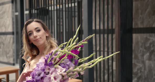 European Woman Posing with Bunch of Flowers at Building