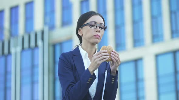 Lady in Business Suit Eating Unhealthy Burger During Lunchtime, Stressful Job
