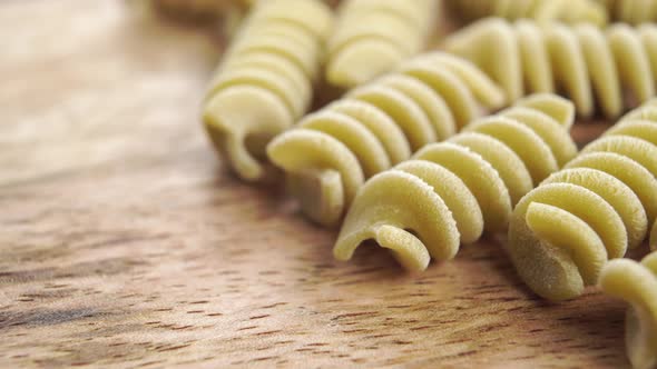 Fusilli Italian uncooked pasta. Green pea macaroni on a kitchen wooden board. Macro